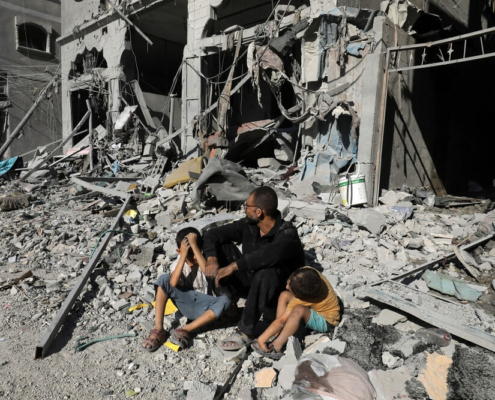 A Palestinian family outside of a destroyed house after an Israeli air strike, in the city of Rafah, south of the Gaza Strip, on October 12 2023.