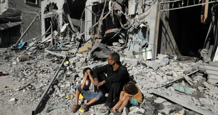 A Palestinian family outside of a destroyed house after an Israeli air strike, in the city of Rafah, south of the Gaza Strip, on October 12 2023.